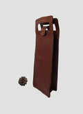 Porte-bouteille de vin artisanal en cuir de vachette marron avec poignée intégrée et fermeture à bouton de col doré, fabriqué à la main en France par MOOAKUIR
