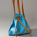 Sac à main Liane en cuir bleu turquoise de veau, anses en cuir tanné végétal camel, fermeture par liens de serrage, fabrication artisanale française
