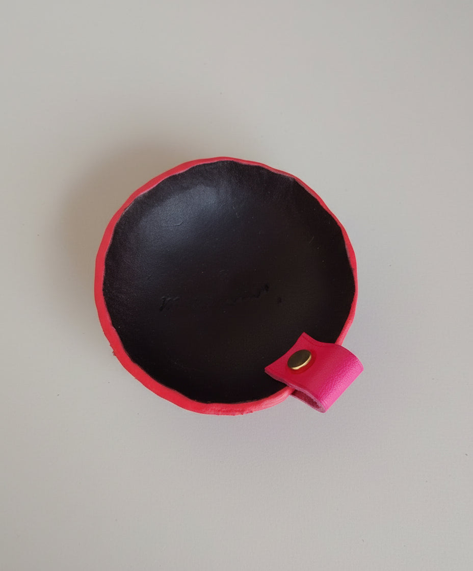 Vide-poche rond artisanal en cuir noir avec tranches teintées rose et petite poignée en cuir de veau rose, fabriqué à la main en France par MOOAKUIR
