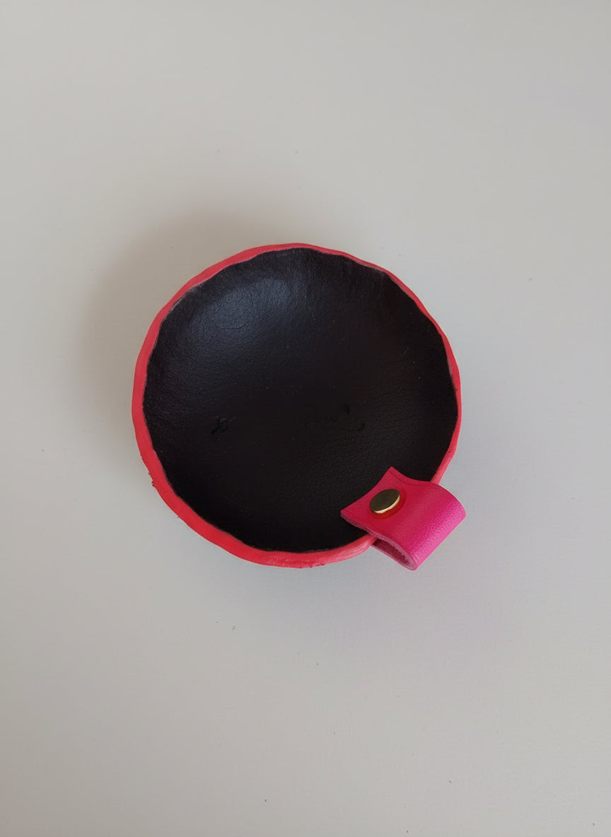 Vide-poche rond artisanal en cuir noir avec tranches teintées rose et petite poignée en cuir de veau rose, fabriqué à la main en France par MOOAKUIR
